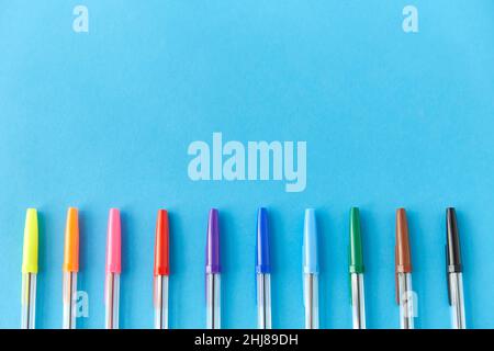row of multicolored pens on blue background Stock Photo