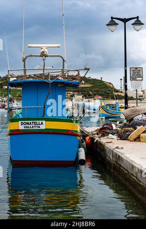 Marsaxlokk, Malta - 01 07 2022: Colorful boats at the harbor with the village in the harbor Stock Photo