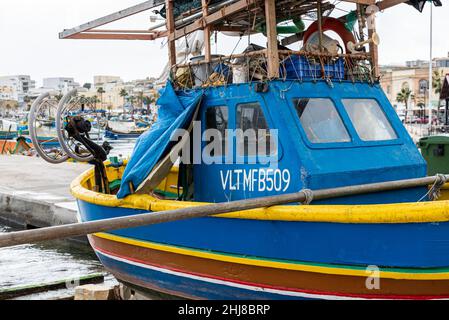 Marsaxlokk, Malta - 01 07 2022: Colorful boats at the harbor with the village in the harbor Stock Photo