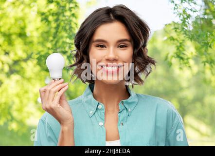 smiling woman holding energy saving lighting bulb Stock Photo