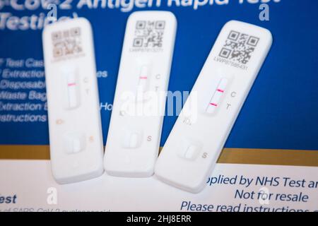 Two positive results and a single negative test result. Three Lateral flow test / LFT / LFD / lateral flow devices kits / device kit, two of which have tested positive (showing two red lines) for COVID 19 virus coronavirus during antigen home testing, in London. UK. To show positive, two red lines will appear. One test shows the positive line to be feint / faint. The third test showing one line only is a negative test. The test (by Flowfex made in China) has detected virus in the sample nasal swab taken from the nose. (128) Stock Photo