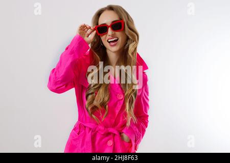 Close up happy girl in red sunglasses and pink coat isolated on white background. excited, shock and surprised young woman in trendy outfit. Fashion a Stock Photo