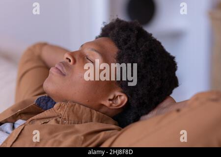 Close-up of african american young man with eyes closed and hands behind head relaxing at home. unaltered, sleeping, relaxation, resting, lifestyle, l Stock Photo