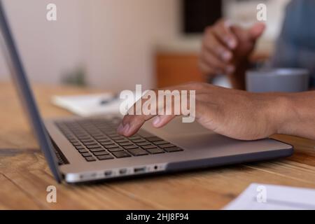 Cropped image of african american young businessman using laptop on table. unaltered, business, close-up, wireless technology, typing, hand, part of a Stock Photo
