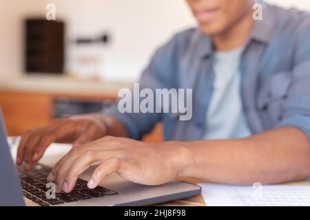 Midsection of african american young businessman using laptop while working at home. unaltered, business, wireless technology, typing, data, hand and Stock Photo