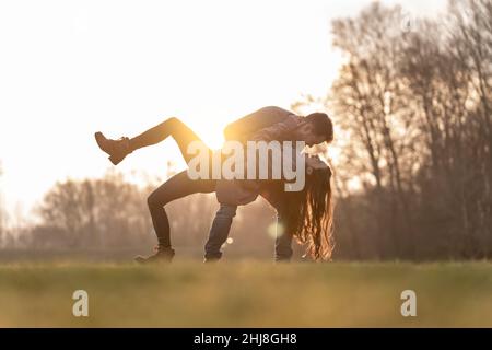 Young heterosexual couple dancing and playing in a park on valentine's day Stock Photo