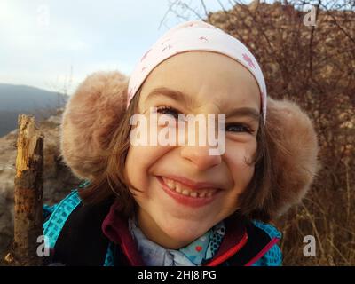 Cute young girl, kid posing with winter ear cap in the outdoors Stock Photo