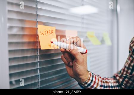 Faceless male employee making notes on sticker Stock Photo