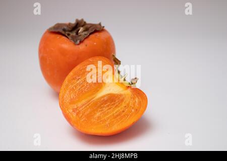 Whole of fresh persimmons and half of persimmons isolated on white background. Stock Photo