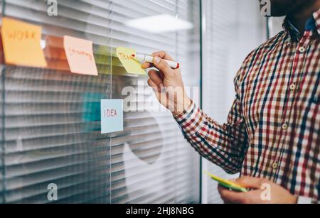 Unrecognizable male employee taking notes on sticky paper Stock Photo