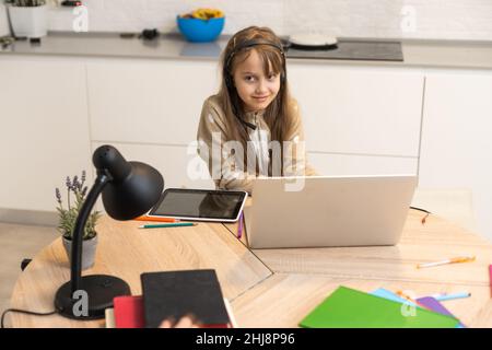 Preteen schoolgirl doing her homework with digital tablet at home. Child using gadgets to study. Education and distance learning for kids Stock Photo