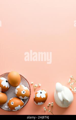 Happy Easter vertical banner design. Plate with painted Easter eggs, bunny and flowers on pastel pink background. Modern minimal style Stock Photo