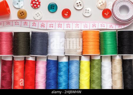 Multi-colored thread buttons measuring tape on a gray background. Stock Photo