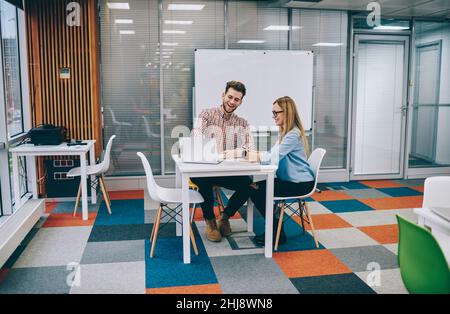 Smiling coworkers using laptop sitting at table in office Stock Photo