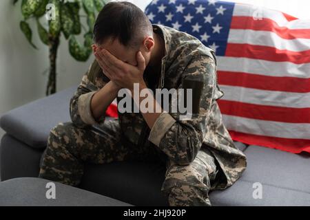 man in military uniform crying USA flag background. Stock Photo