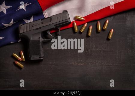 Black pistol and bullets with an American flag on a black wood painted background Stock Photo