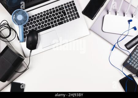 Top view to old laptop computers, digital tablets, mobile phones, many used electronic gadgets devices on white table. Planned obsolescence, e-waste Stock Photo