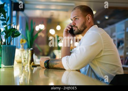 Pensive man talking on phone in cafe Stock Photo