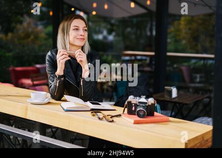 Woman with notebook and camera with smartphone at cafe Stock Photo
