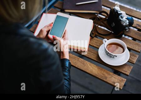 Faceless woman using smartphone in cafeteria Stock Photo