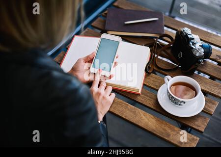 Anonymous female in cafe using smartphone Stock Photo