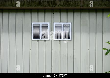 Two ventilation grilles on a green building wall. Stock Photo