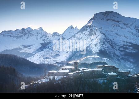 Snowy village and Apuan Alps mountains in winter. Nicciano, Garfagnana, Tuscany, Italy, Europe Stock Photo