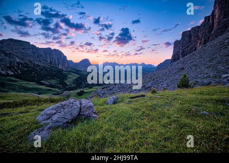 Rock faces of the Sella group at right, Puez group and Mt. Sassongher at left, seen from Gardena Pass at sunrise. Stock Photo