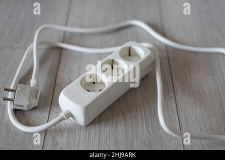 white extension cord on the wooden floor Stock Photo