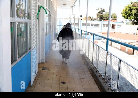 Sanitizer Daniela Guerrero  sprays disinfectant inside  facilities of a school as attempt to avoid the increase in infections by the new Omicron varia Stock Photo