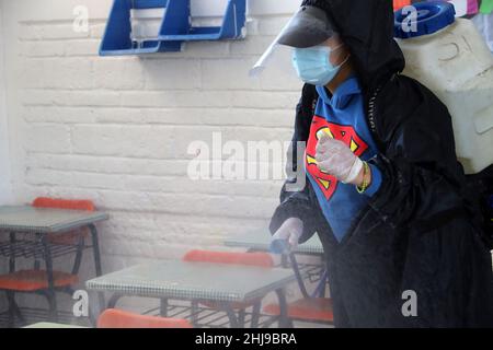 Sanitizer Daniela Guerrero  sprays disinfectant inside  facilities of a school as attempt to avoid the increase in infections by the new Omicron varia Stock Photo