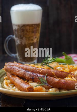 Traditional cooked sauerkraut with sausages and beer. Stewed sour cabbage with grilled sausages. Stock Photo