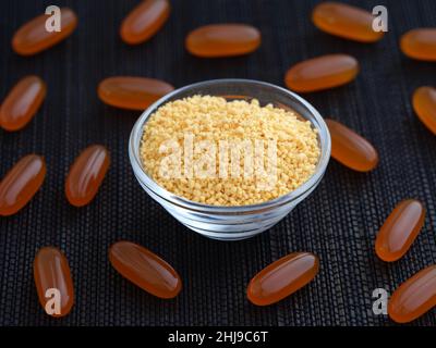 Soy lecithin in a glass bowl with soy lecithin softgels around it. Low key. Close up. Stock Photo