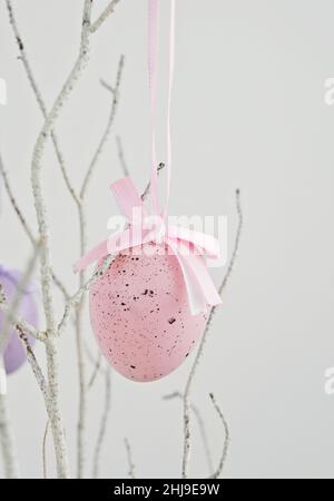 Pink decorative Easter egg hanging on dry branch on white Stock Photo