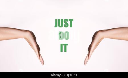 Motivational horizontal poster. Women's hands in a pointing gesture. Green motivating inscription 'Just Do It' Stock Photo