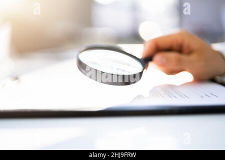 Businessman Looking At Document Through Magnifying Glass Stock Photo