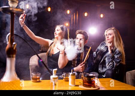 Friends party in hookah lounge smoking shisha night time Stock Photo