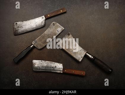 Close up vintage butcher meat cleavers on cutting board or grunge brown stone table surface with copy space, elevated top view, directly above Stock Photo