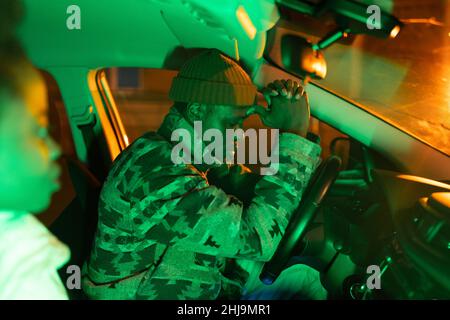Depressed african man sitting in car with girlfriend at night time, frustrated black guy in auto Stock Photo