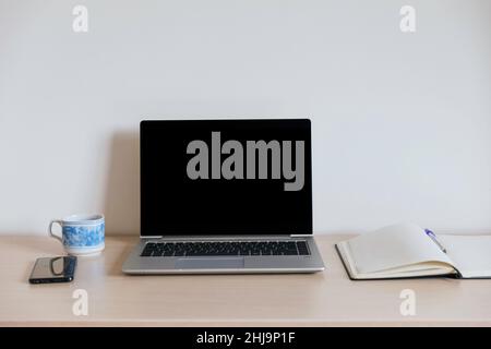 Workspace with black screen computer, open notepad, pen, coffee cup and smartphone. No people with white background. Copy space Stock Photo