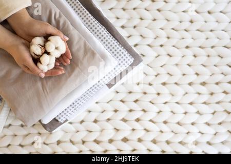 Stack of folded warm blankets with different design patterns and cotton branch on grey background Stock Photo