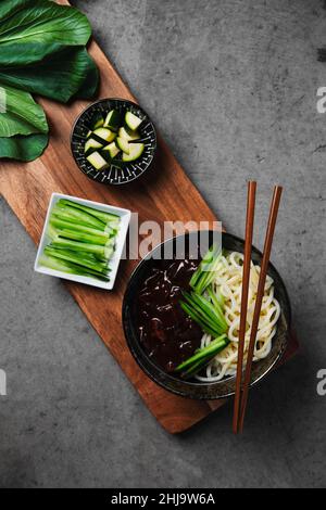 Traditional Korean black beef noodle bowl with cucumber and zucchini green vegetables. Stock Photo