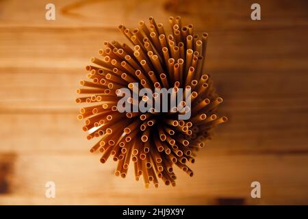 Ecologically friendly and biodegradable wheat straws on top of a rustic wooden table background. Stock Photo