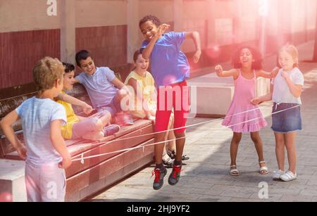 Mexican boy playing rubber band jumping game with friends Stock Photo