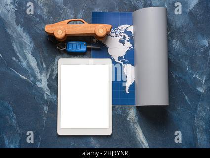 Tablet computer with toy car, key and map on grunge background Stock Photo