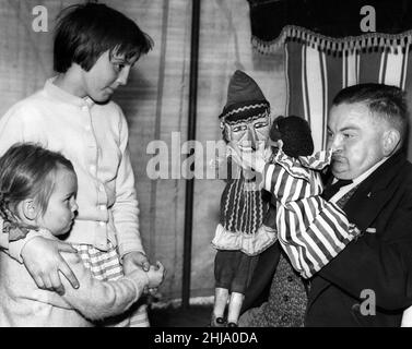 Mr Derek De Cora, who is giving Punch and Judy shows at the Tyneside Summer Exhibition, gives a close up view of two of the puppets to two girls. Exhibition Park, Newcastle. 23rd August 1963. Stock Photo