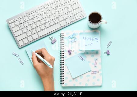 Woman with pen, stationery, computer keyboard and cup of coffee on blue background Stock Photo
