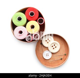 Wooden box with sewing thread spools, buttons and pins on white background Stock Photo
