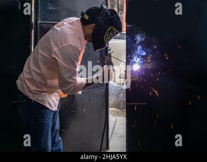 Welder waring protective mask repairs a door in Jinotega, Nicaragua. Stock Photo