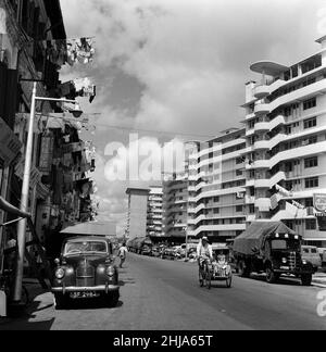 Scenes in Chinatown, Singapore. Upper Hokien Street, where old meets new. Clean washing is poked out from the windows from both old and new buildings as sleek limousines or trishaws make their way during the morning heat. 6th February 1962. Stock Photo